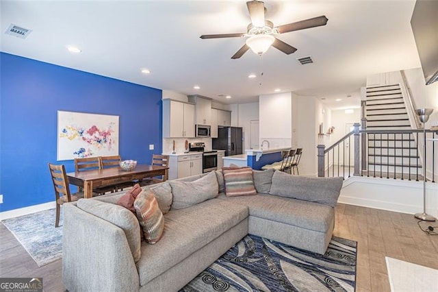 living room with light hardwood / wood-style flooring and ceiling fan