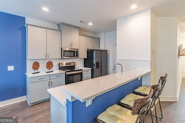 kitchen with a kitchen bar, kitchen peninsula, and appliances with stainless steel finishes