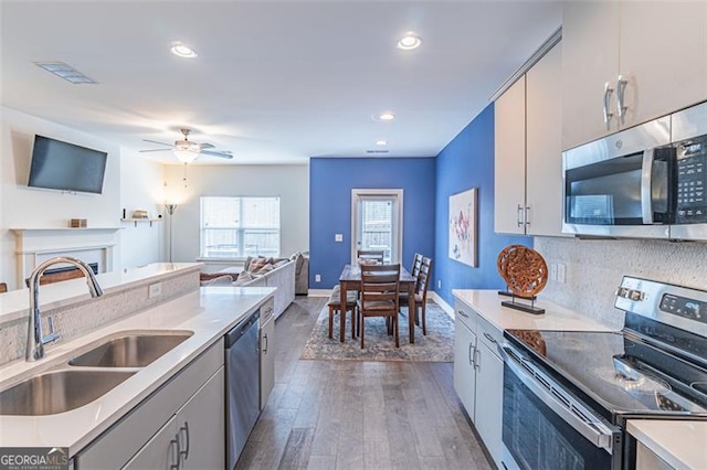 kitchen with tasteful backsplash, stainless steel appliances, ceiling fan, dark wood-type flooring, and sink