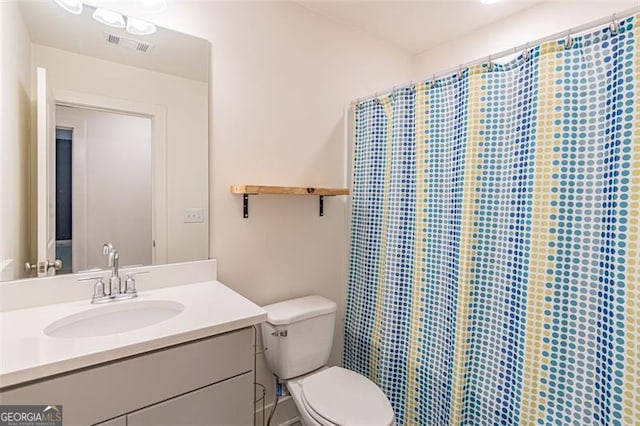 bathroom with curtained shower, vanity, and toilet