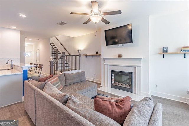 living room featuring ceiling fan, light wood-type flooring, and sink