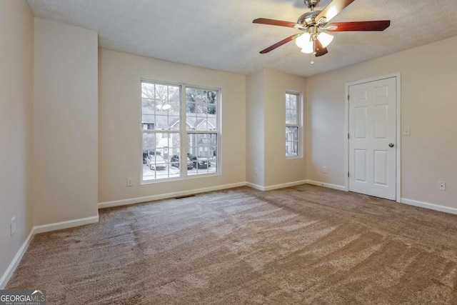 unfurnished room with carpet flooring, ceiling fan, and a textured ceiling