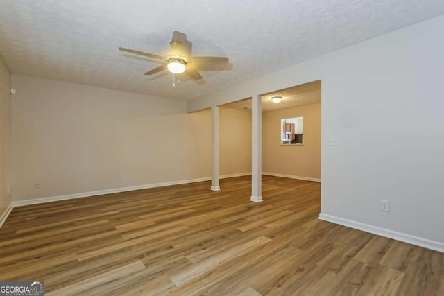 basement with a textured ceiling, hardwood / wood-style flooring, and ceiling fan