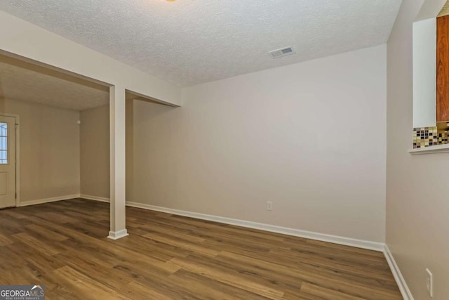 basement featuring wood-type flooring and a textured ceiling