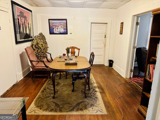 dining room with dark wood-type flooring and a paneled ceiling