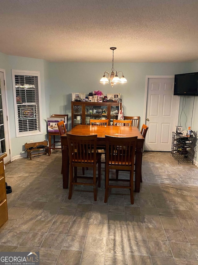 dining space with a textured ceiling and a chandelier