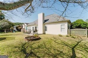 back of house with a yard and an outdoor fire pit