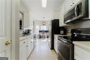 kitchen with hanging light fixtures, white cabinets, stainless steel appliances, and sink