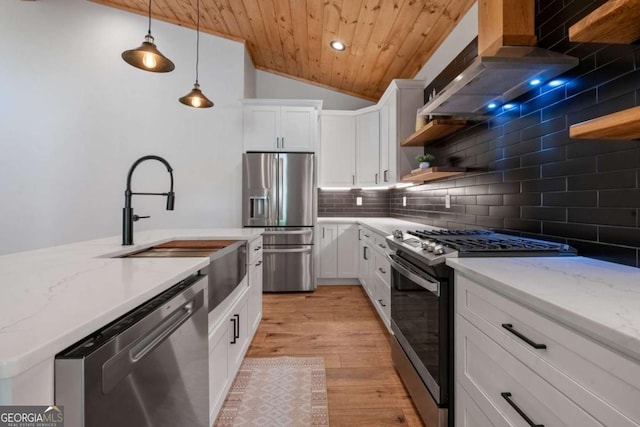 kitchen with pendant lighting, white cabinets, vaulted ceiling, light stone countertops, and appliances with stainless steel finishes