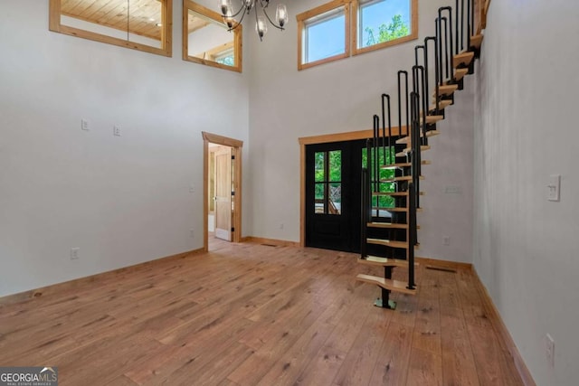 entryway featuring light hardwood / wood-style flooring, wood ceiling, a high ceiling, and a notable chandelier