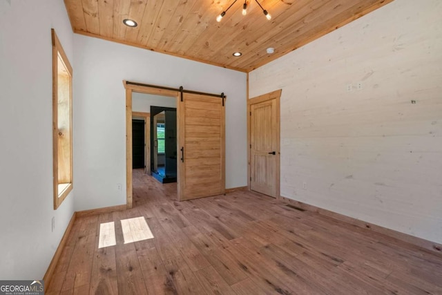 spare room with a barn door, wood ceiling, and light wood-type flooring