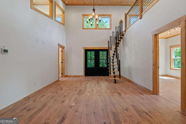 entryway with light hardwood / wood-style flooring, a high ceiling, and an inviting chandelier