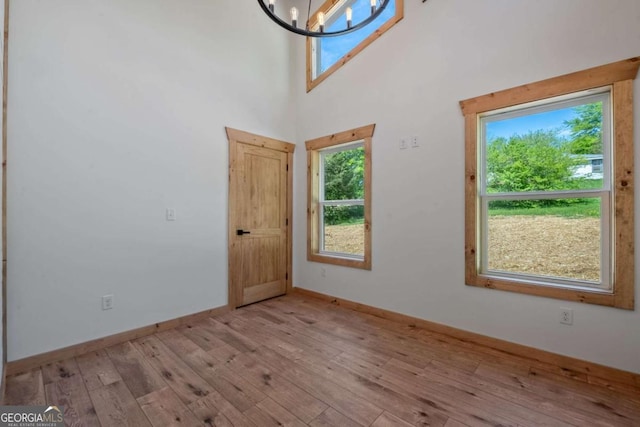 interior space with light hardwood / wood-style flooring, a towering ceiling, and a notable chandelier