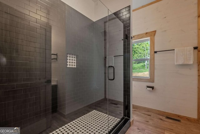 bathroom with hardwood / wood-style flooring and walk in shower