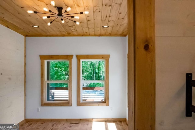 interior space with light hardwood / wood-style floors, wooden ceiling, and a chandelier