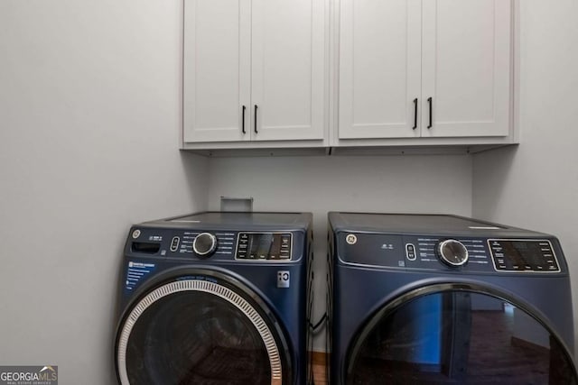 clothes washing area featuring washer and clothes dryer and cabinets