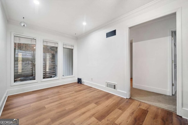 empty room featuring crown molding and wood-type flooring