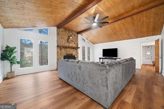 living room with vaulted ceiling with beams, a stone fireplace, ceiling fan, wooden ceiling, and hardwood / wood-style flooring