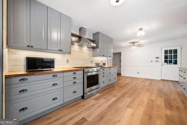 kitchen featuring gas range, gray cabinetry, light hardwood / wood-style floors, tasteful backsplash, and wooden counters