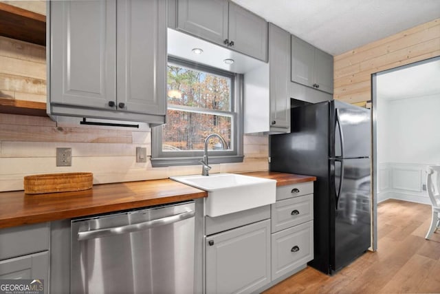 kitchen featuring sink, wood counters, dishwasher, and gray cabinetry