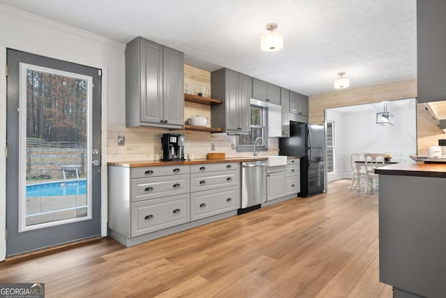 kitchen featuring light hardwood / wood-style flooring, wooden counters, dishwasher, gray cabinetry, and black refrigerator