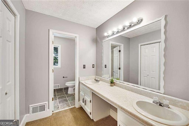 bathroom featuring a textured ceiling, toilet, and vanity