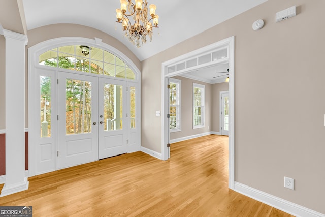 entryway featuring lofted ceiling, french doors, ceiling fan with notable chandelier, light wood-type flooring, and ornamental molding