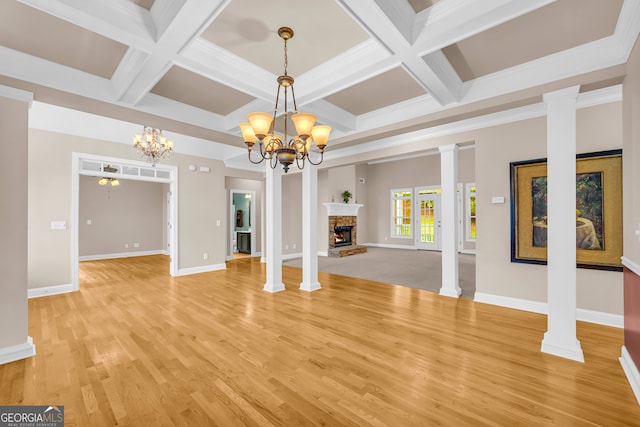 unfurnished living room with hardwood / wood-style floors, a notable chandelier, ornate columns, and ornamental molding