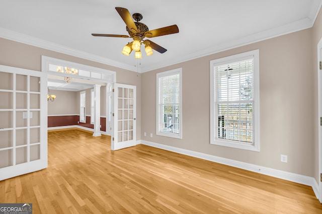 spare room featuring ceiling fan with notable chandelier, light hardwood / wood-style floors, ornamental molding, and french doors