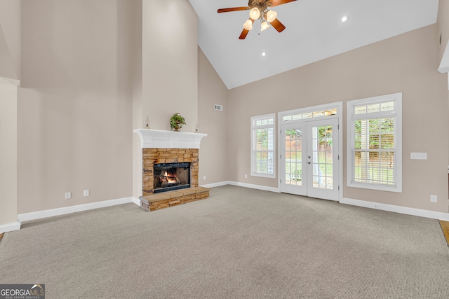 unfurnished living room with french doors, ceiling fan, high vaulted ceiling, a fireplace, and carpet floors