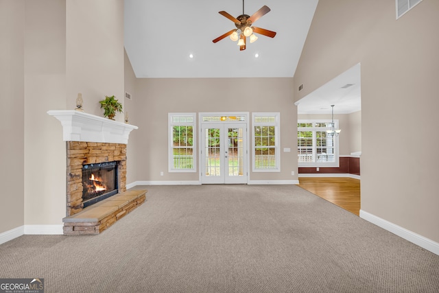 unfurnished living room with carpet, high vaulted ceiling, french doors, ceiling fan, and a fireplace