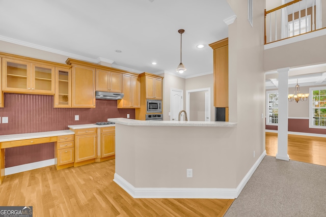 kitchen featuring crown molding, stainless steel microwave, light wood-type flooring, and hanging light fixtures