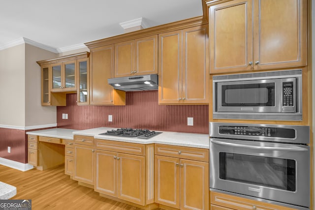 kitchen featuring appliances with stainless steel finishes, light hardwood / wood-style floors, and ornamental molding