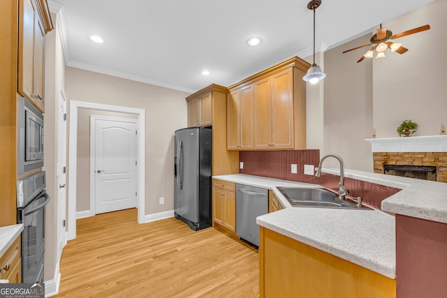 kitchen featuring ceiling fan, sink, stainless steel appliances, a stone fireplace, and light wood-type flooring