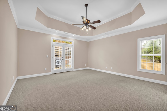 carpeted spare room featuring french doors, a raised ceiling, ceiling fan, and crown molding