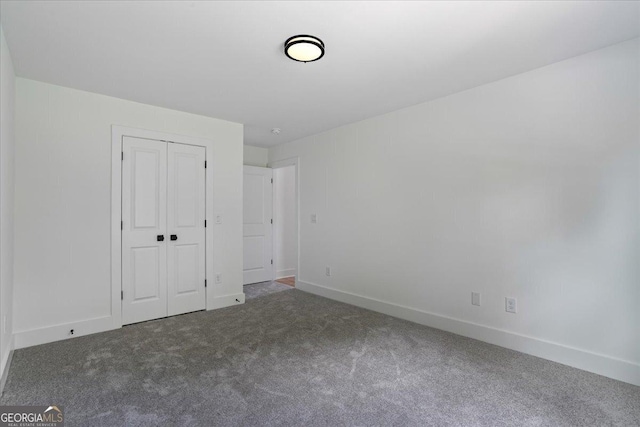 unfurnished bedroom featuring a closet and dark colored carpet