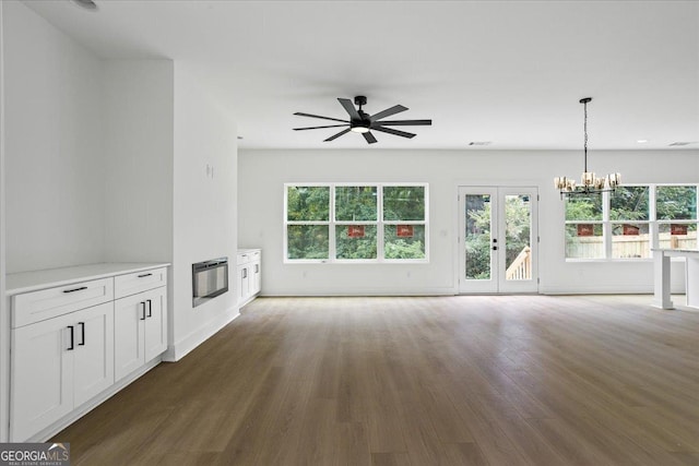 unfurnished living room featuring ceiling fan with notable chandelier, dark hardwood / wood-style floors, heating unit, and french doors