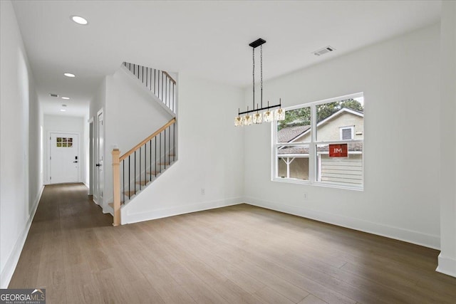 unfurnished dining area with hardwood / wood-style flooring and a notable chandelier