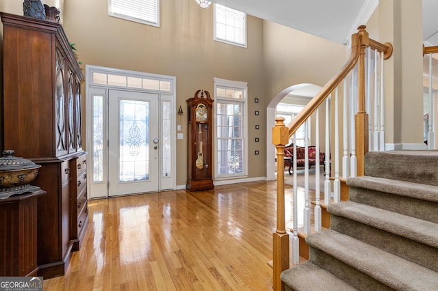 entryway featuring a towering ceiling, light wood-type flooring, and a wealth of natural light