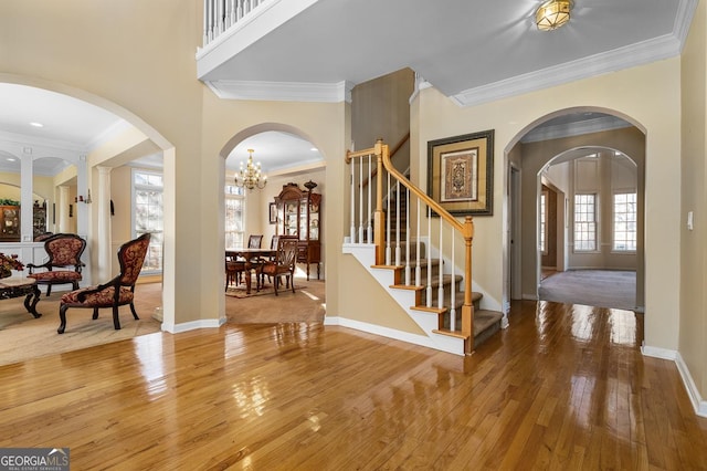 entryway with crown molding, hardwood / wood-style flooring, and an inviting chandelier