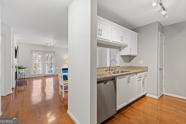 kitchen with light wood-type flooring, white cabinetry, stainless steel dishwasher, and sink