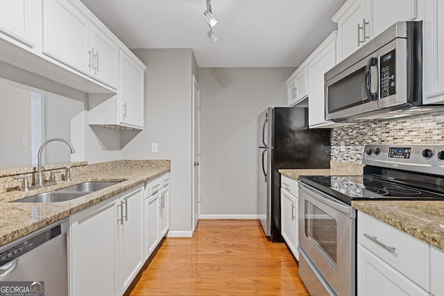 kitchen with white cabinets, sink, appliances with stainless steel finishes, and light hardwood / wood-style flooring