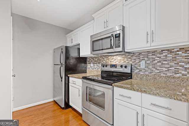 kitchen featuring white cabinetry, light wood-type flooring, light stone counters, and appliances with stainless steel finishes