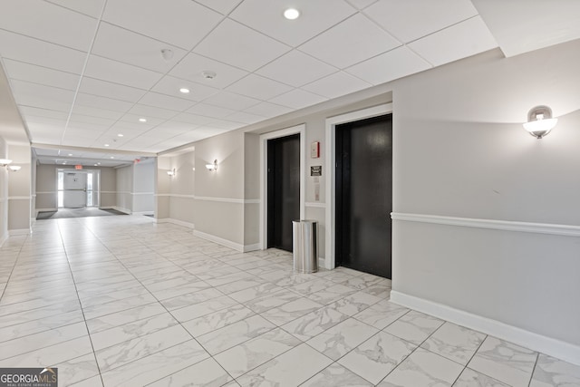 unfurnished room featuring elevator and a paneled ceiling