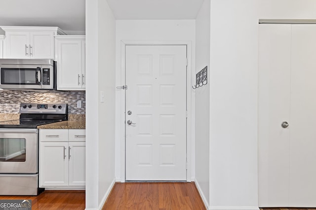 kitchen featuring white cabinetry, dark stone counters, light wood-type flooring, and appliances with stainless steel finishes