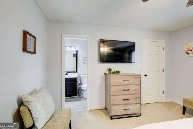 bedroom with light carpet, a textured ceiling, and connected bathroom