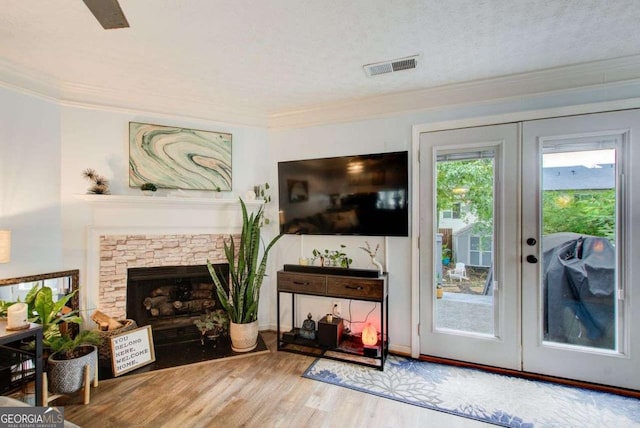 entryway with a fireplace, french doors, crown molding, and hardwood / wood-style floors