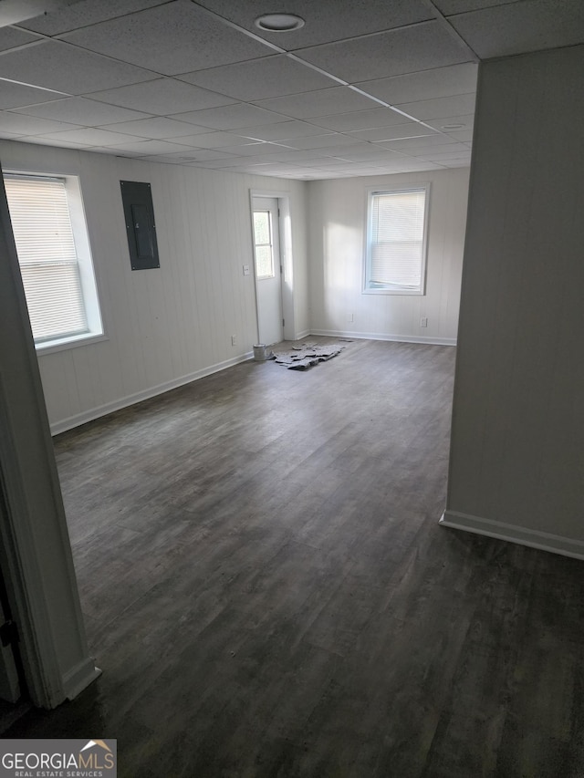 unfurnished room with electric panel, dark hardwood / wood-style flooring, and a drop ceiling