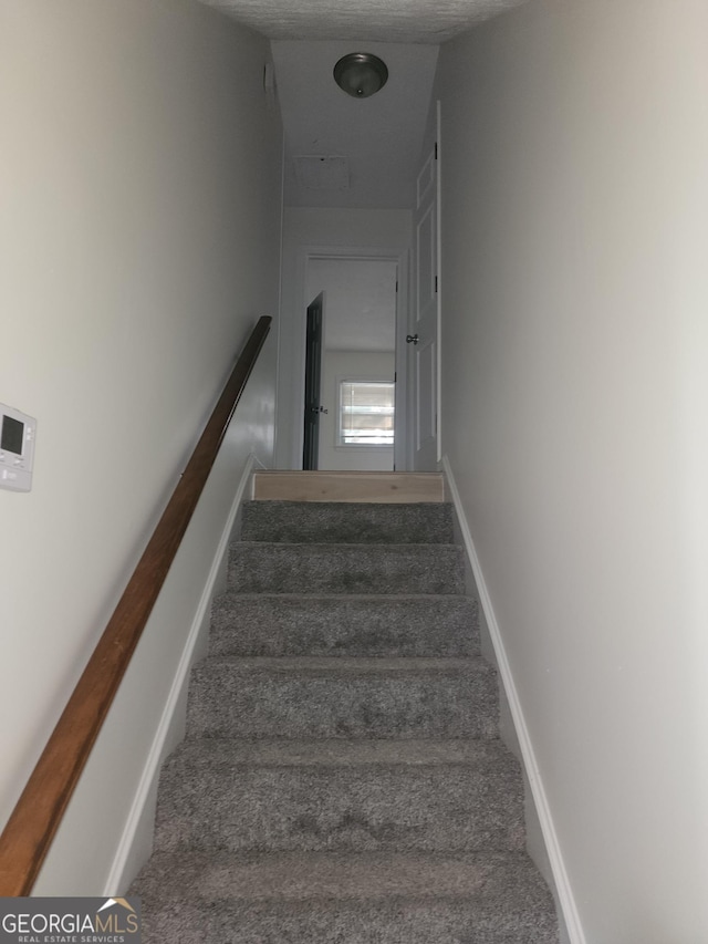 stairs featuring carpet floors and a textured ceiling