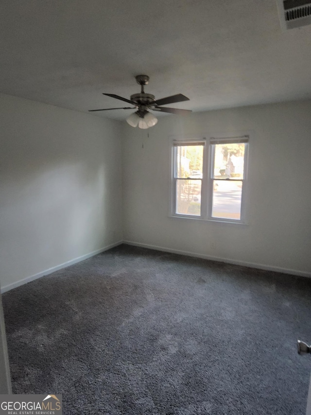 empty room with ceiling fan and dark carpet